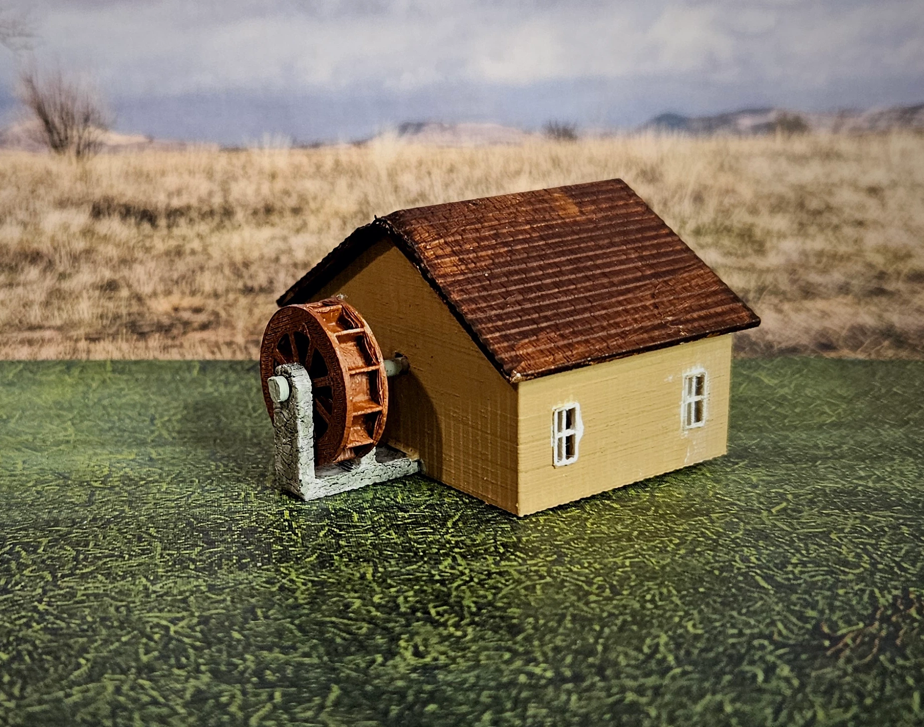 Side view of N scale waterwheel with large building